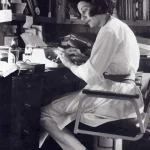 Anne Sexton sentada en su escritorio mecanografiando textos
