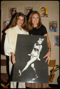 Gloria Steinem junto a Kirstie Alley sosteniendo una imagen de Gloria como conejita Playboy.